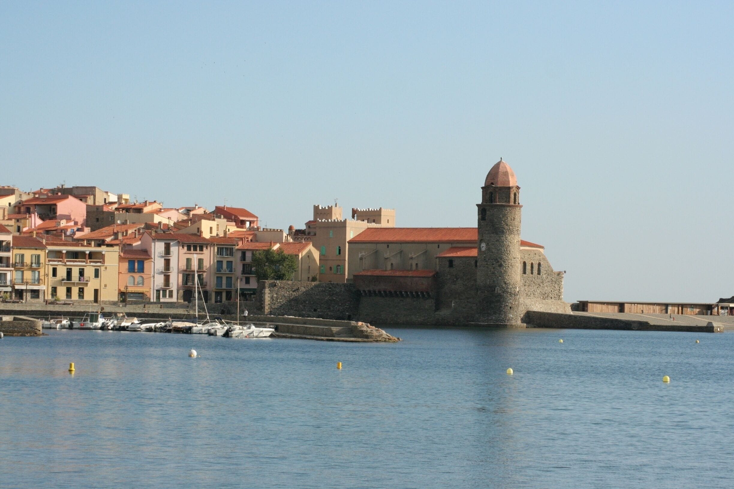 Un pueblo costero con edificios históricos y una torre destacada junto al agua.