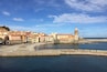 Un pueblo costero con edificios históricos, una torre destacada y una playa de arena.