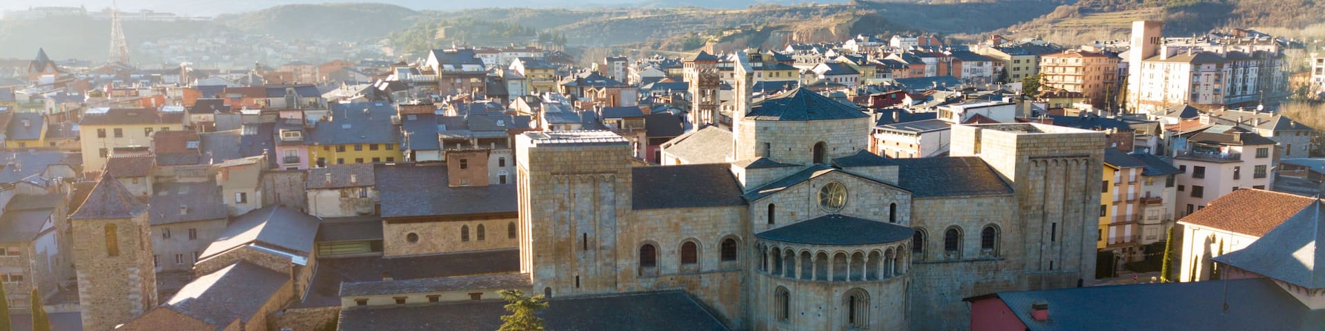 A historic town with a prominent church, surrounded by mountains and various buildings.