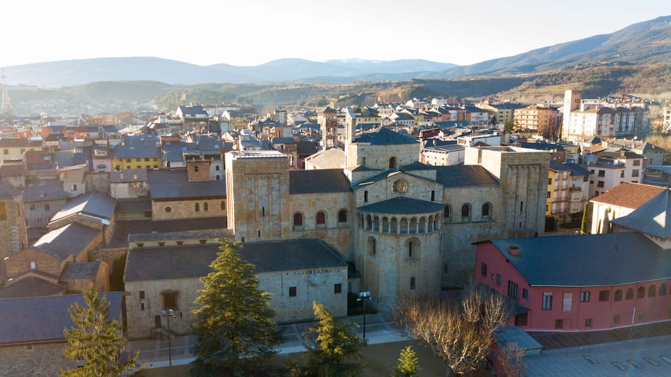 A historic town with a prominent church, surrounded by mountains and various buildings.