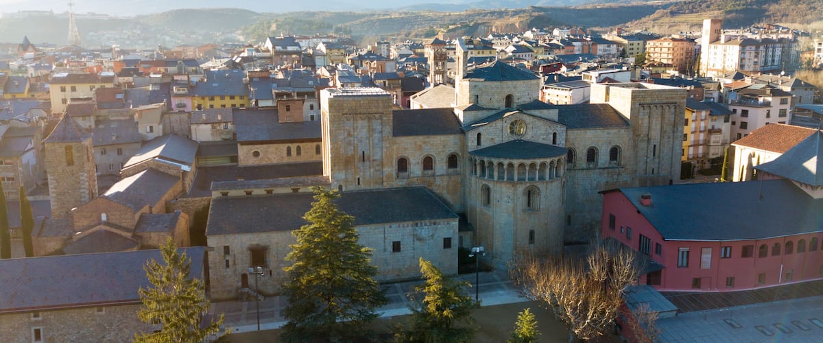 A historic town with a prominent church, surrounded by mountains and various buildings.