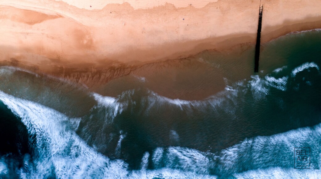 Aerial view of the beach where the cool ocean water meets the warm sand, creating a stunning contrast of blues and golds, Seignosse ocean, Nouvelle-Aquitaine, France.