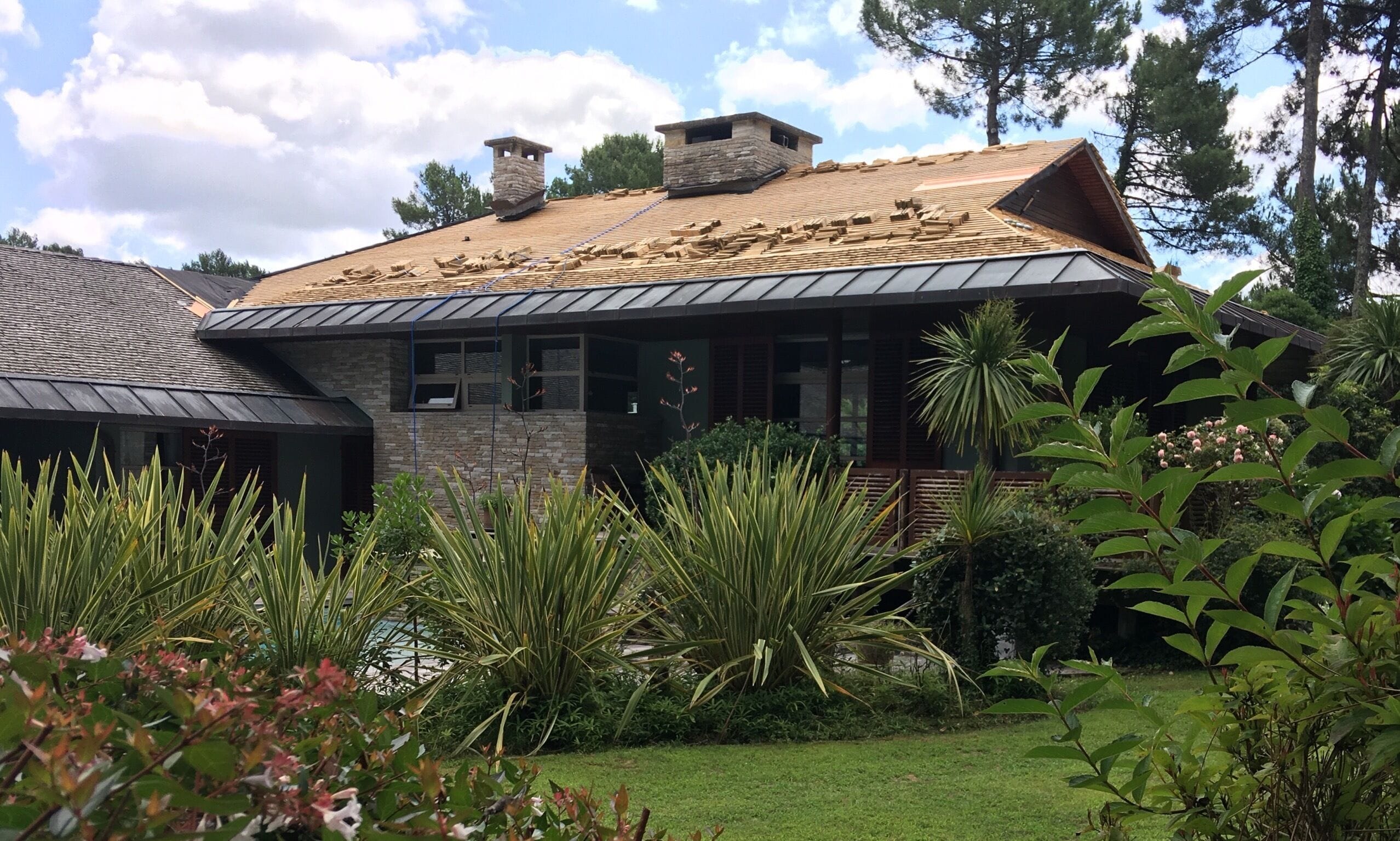 Wood shingles being laid on a roof with a low incline on a mansion in Seignosse, Aquitaine, France