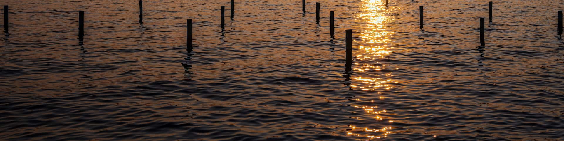 A sunset over a body of water with a bridge in the distance.
