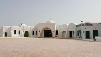 A white building with green doors and a dome, labeled "MUSEE DE GUELLALA".