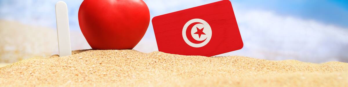 I love Tunisia. Flag of Tunisia on the beach with a red heart. vacation and travel concept.