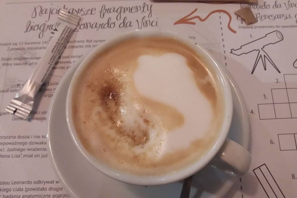 A cup of coffee with latte art on a menu.