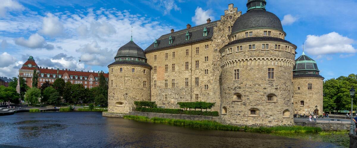 A historic castle with multiple domes and towers, situated by a river.