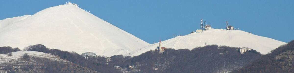 Ein mit Schnee bedeckter Berg mit Seilbahn und Gebäuden an den Hängen.