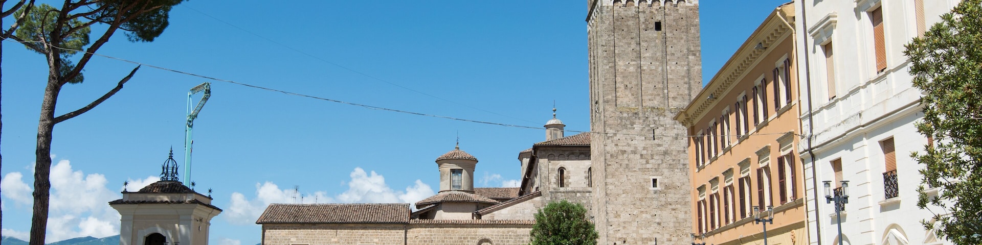 A historic building with a prominent tower, a courtyard, and surrounding greenery.
