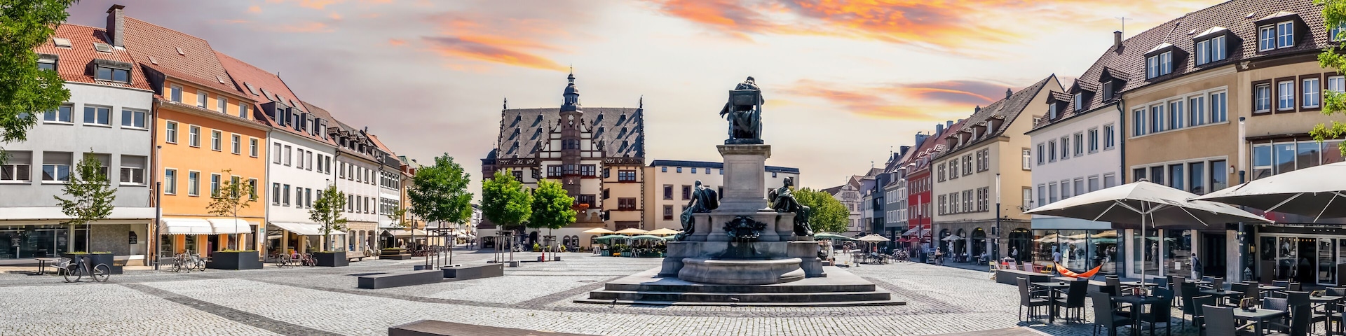 A cobblestone square with a central fountain, surrounded by historic buildings and outdoor seating areas.