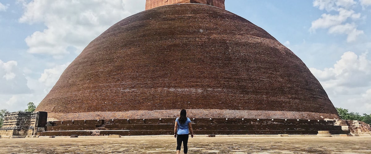 A large brick dome structure with a smaller brick building on top, set against a partly cloudy sky.