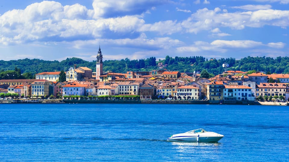 A coastal town with colorful buildings, a prominent tower, and a boat on the water.