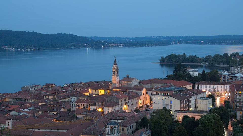 A riverside town with a prominent clock tower, historic buildings, and a calm lake.