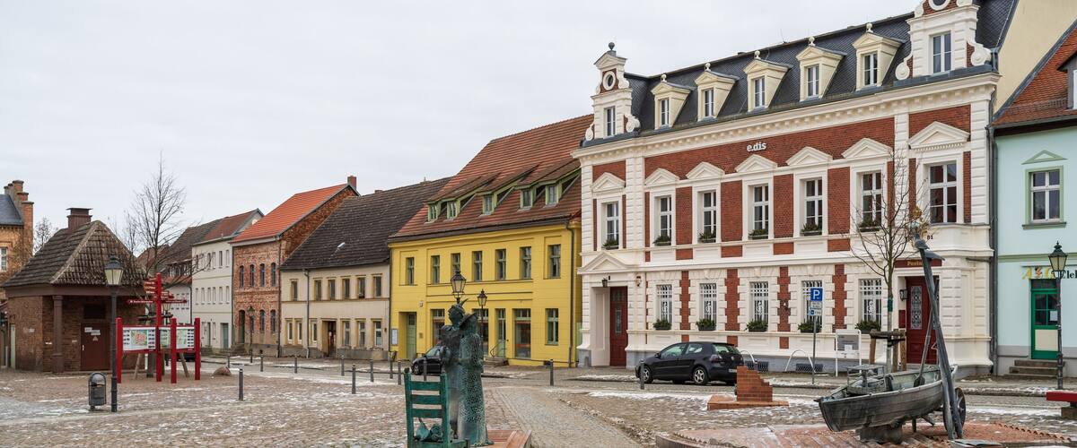 A cobblestone square with historic buildings, a statue, and a boat.