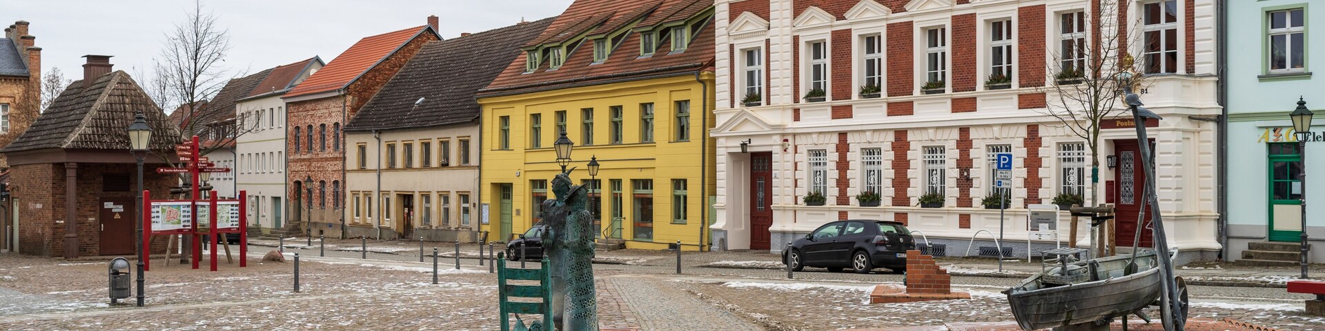 A cobblestone square with historic buildings, a statue, and a boat.