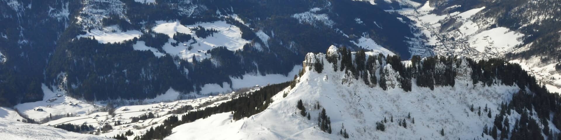 A snow-covered mountain range with a ski slope in the foreground.