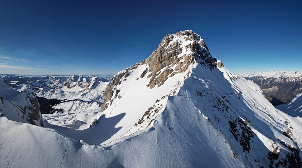 Panoramic aerial view of the majestic Pointe Percee, snow-capped mountain peak piercing the clear blue sky, Le Grand-Bornand, Auvergne-Rhone-Alpes, France.