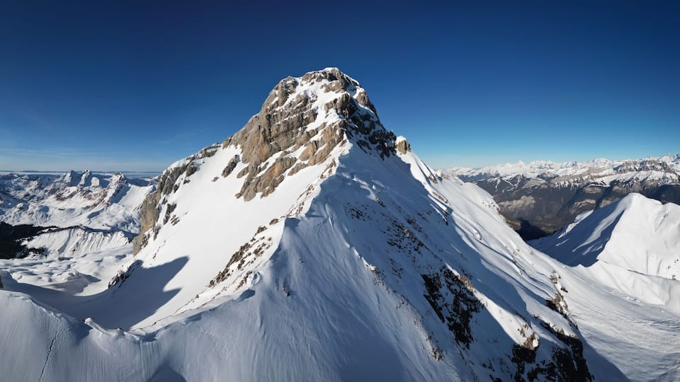 A snow-covered mountain peak with a clear sky.