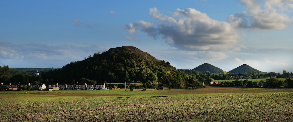 A rural landscape with a hill, a church, and a field.