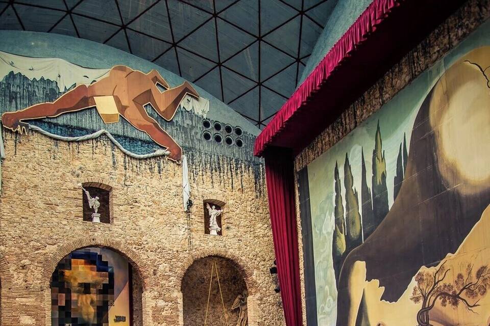 Un interior con paredes de piedra, un gran mural y una zona de escenario.