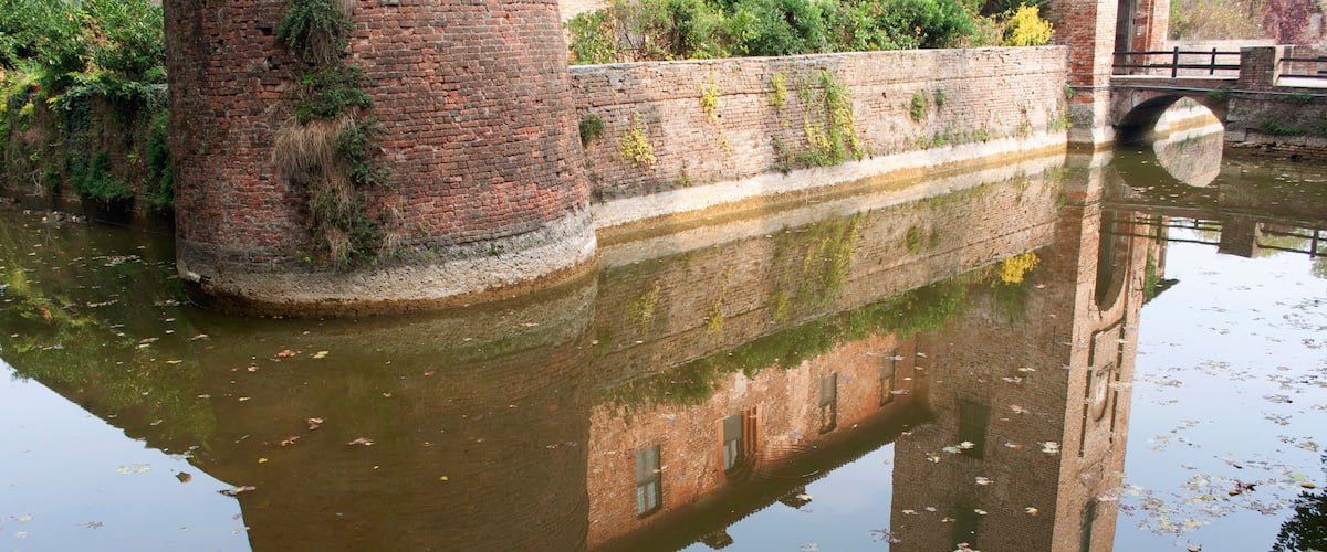 A brick tower, a bridge, and a canal with reflections.