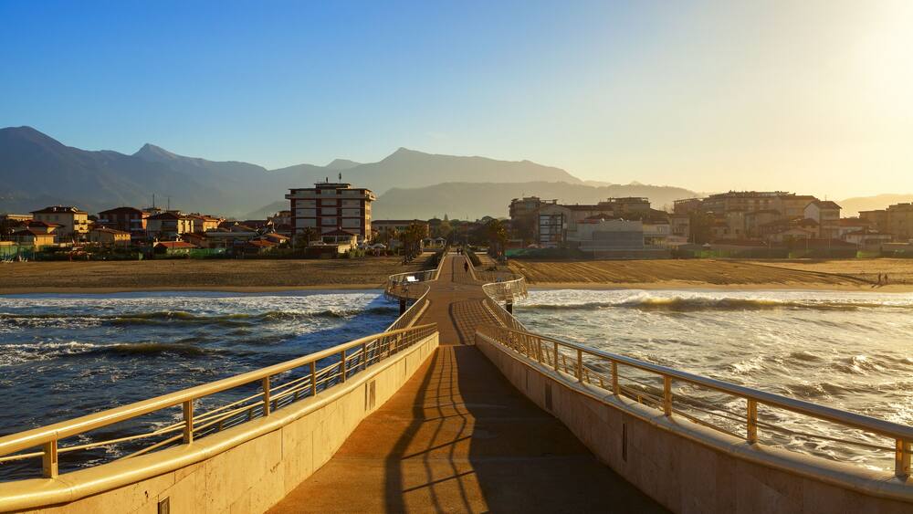 A coastal walkway with a view of the ocean and mountains in the background.