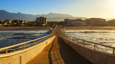 A coastal walkway with a view of the ocean and mountains in the background.