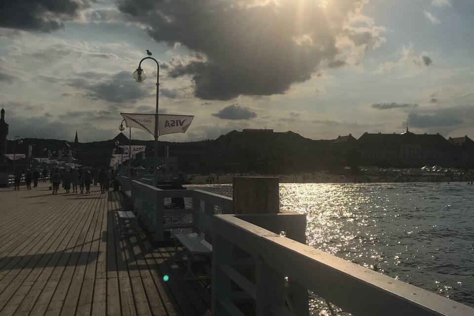 Um cais de madeira que se estende sobre a água, com um pôr do sol ao fundo.