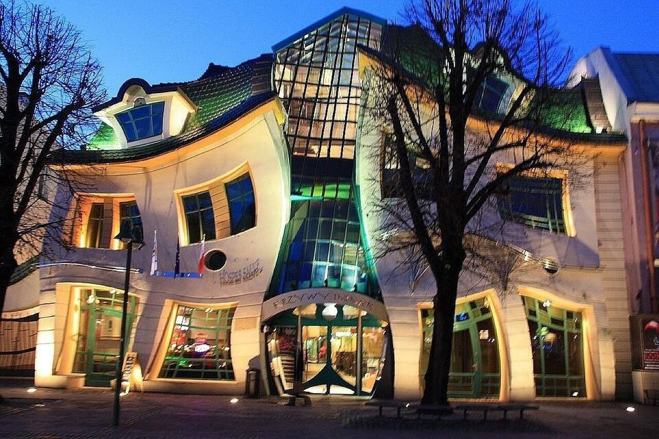 Um edifício moderno com fachada curva e grandes janelas, rodeado por árvores.