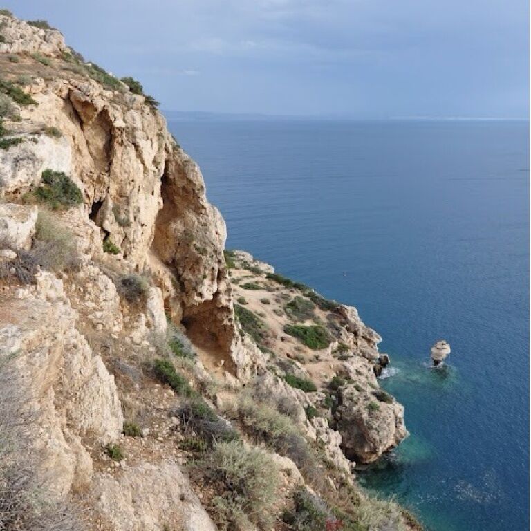 Cliff with caves at Melagavi Lighthouse overlooking Gulf of Corinth.