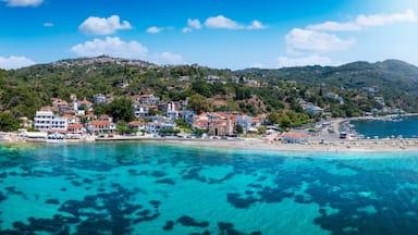 Uma cidade costeira com edifícios numa encosta, águas turquesa cristalinas e uma praia arenosa.