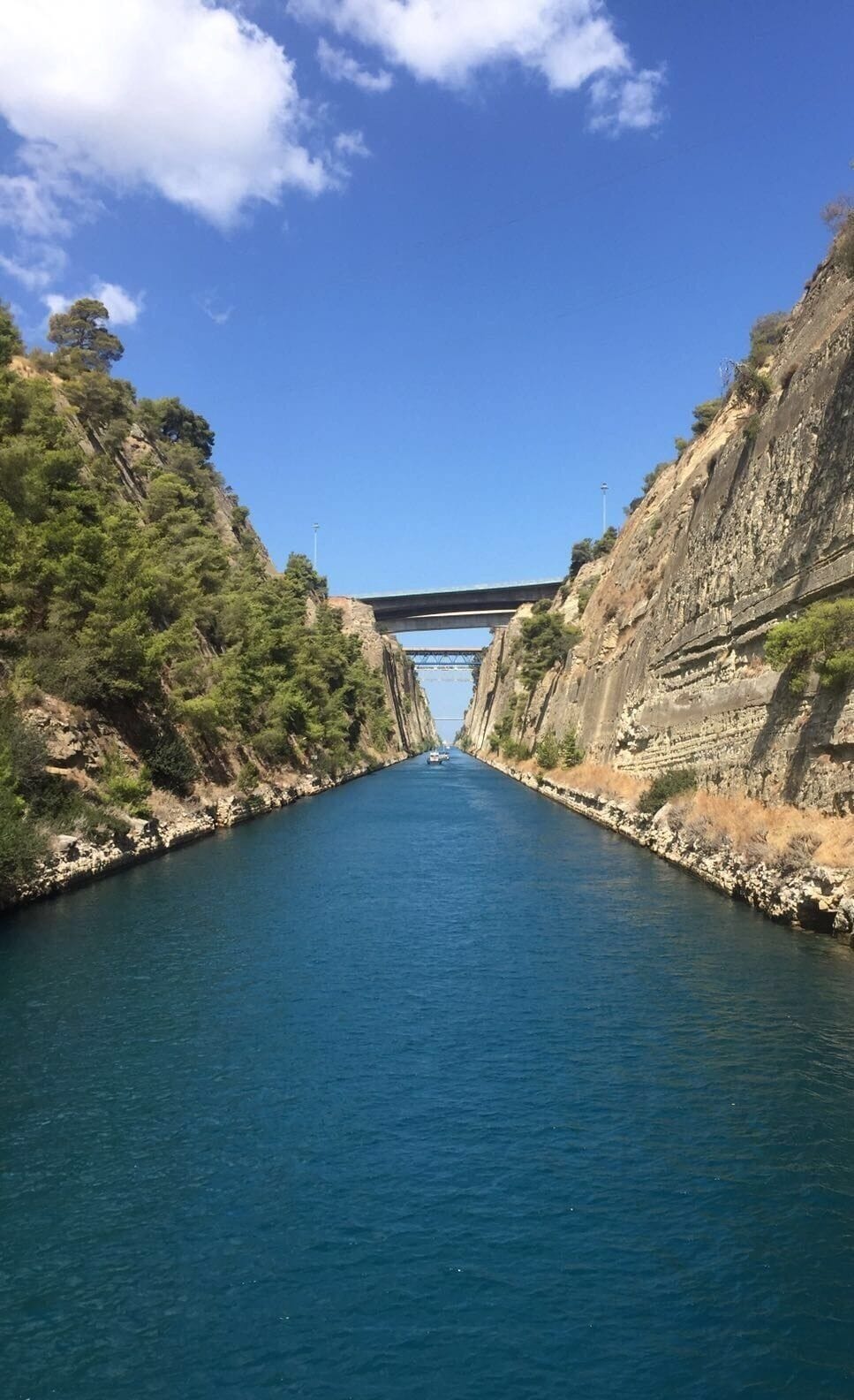 A narrow waterway flanked by steep cliffs, with a bridge spanning the width of the channel.