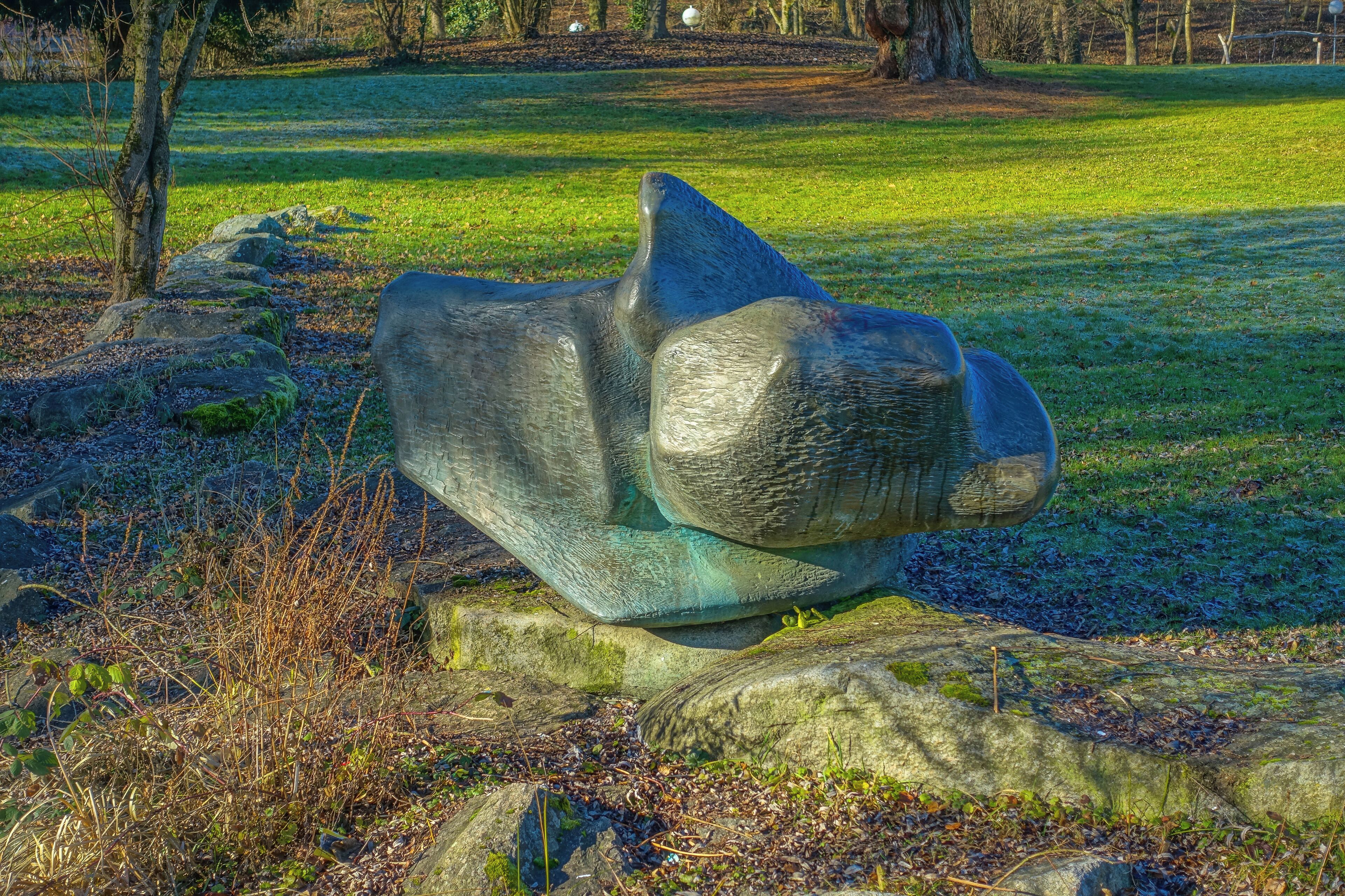 A stone sculpture of a bear in a park.