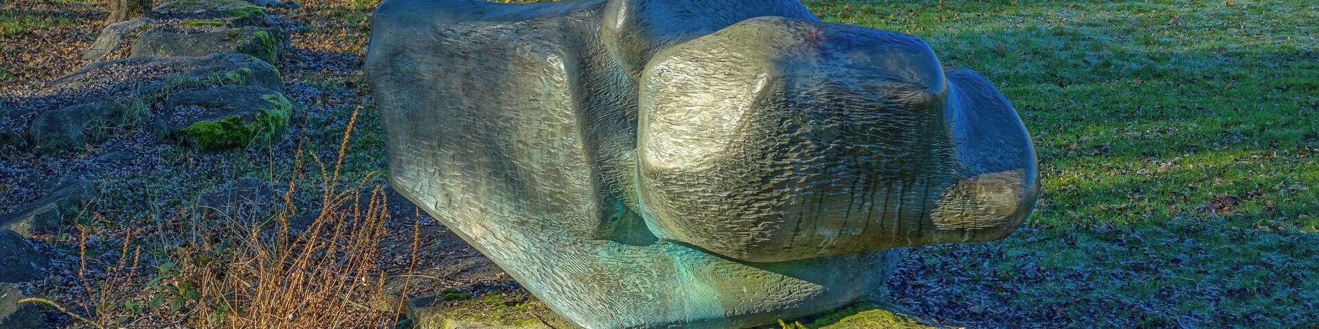 A stone sculpture of a bear in a park.