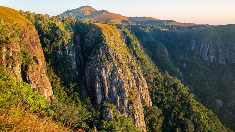 A mountainous landscape with steep cliffs and dense green vegetation.