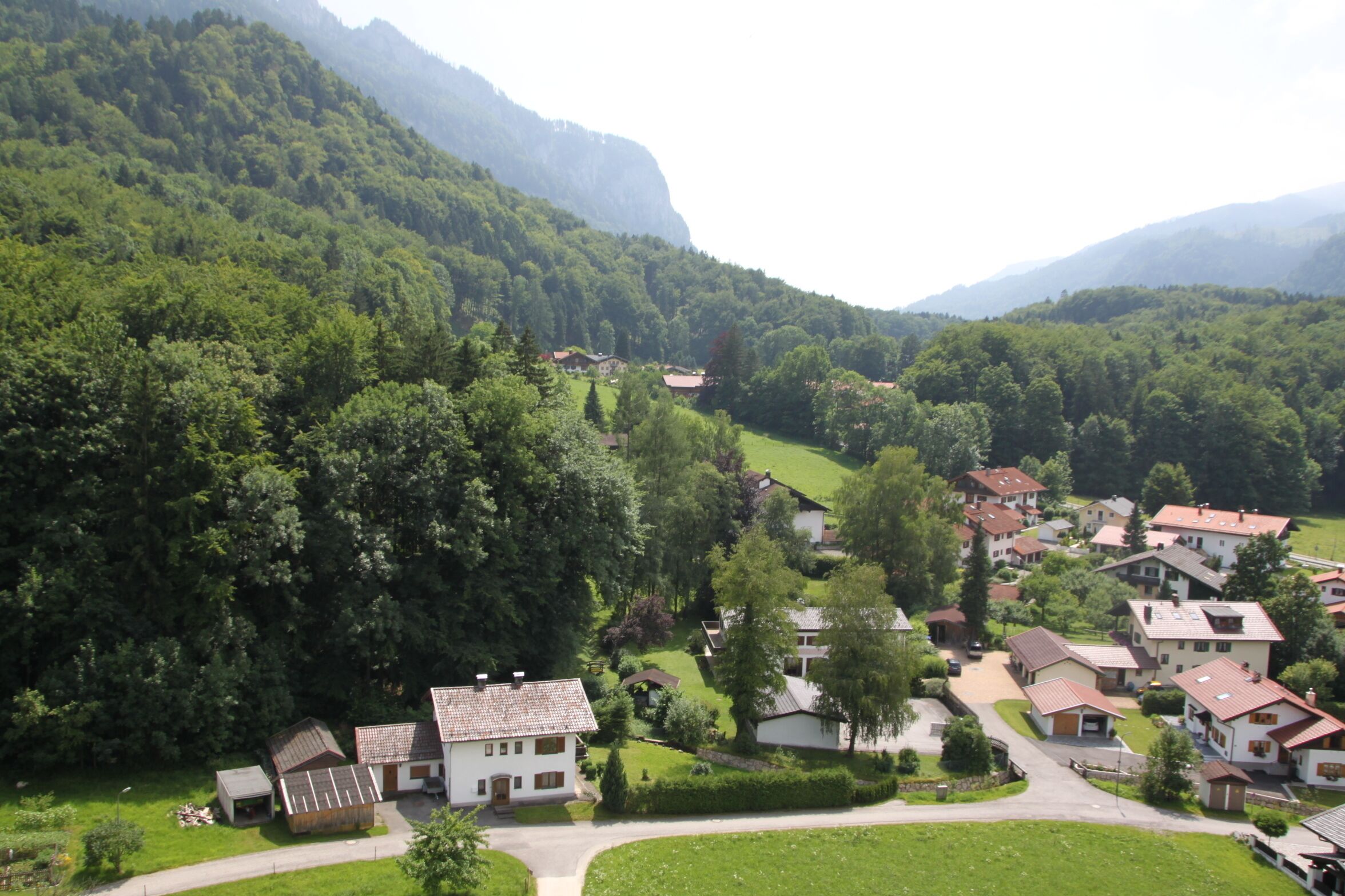 A village nestled in a valley surrounded by lush green mountains.