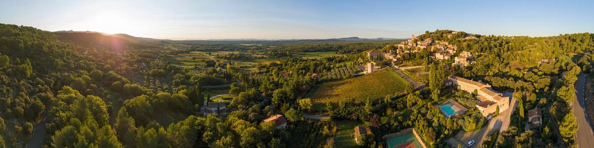 Aerial view of a picturesque village surrounded by tranquil fields and trees at sunset, Moissac-Bellevue, Var, France.