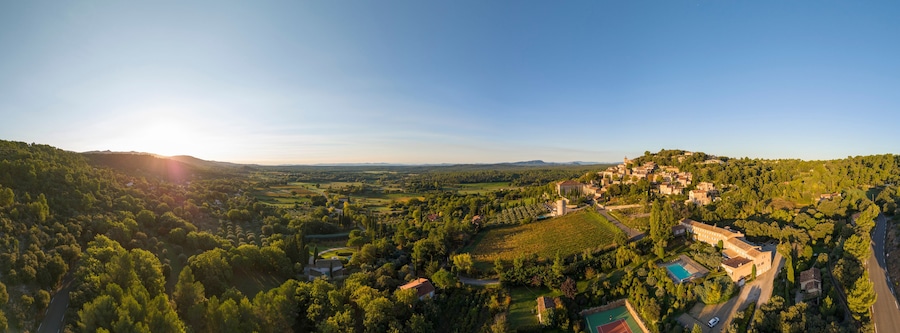 Aerial view of a picturesque village surrounded by tranquil fields and trees at sunset, Moissac-Bellevue, Var, France.