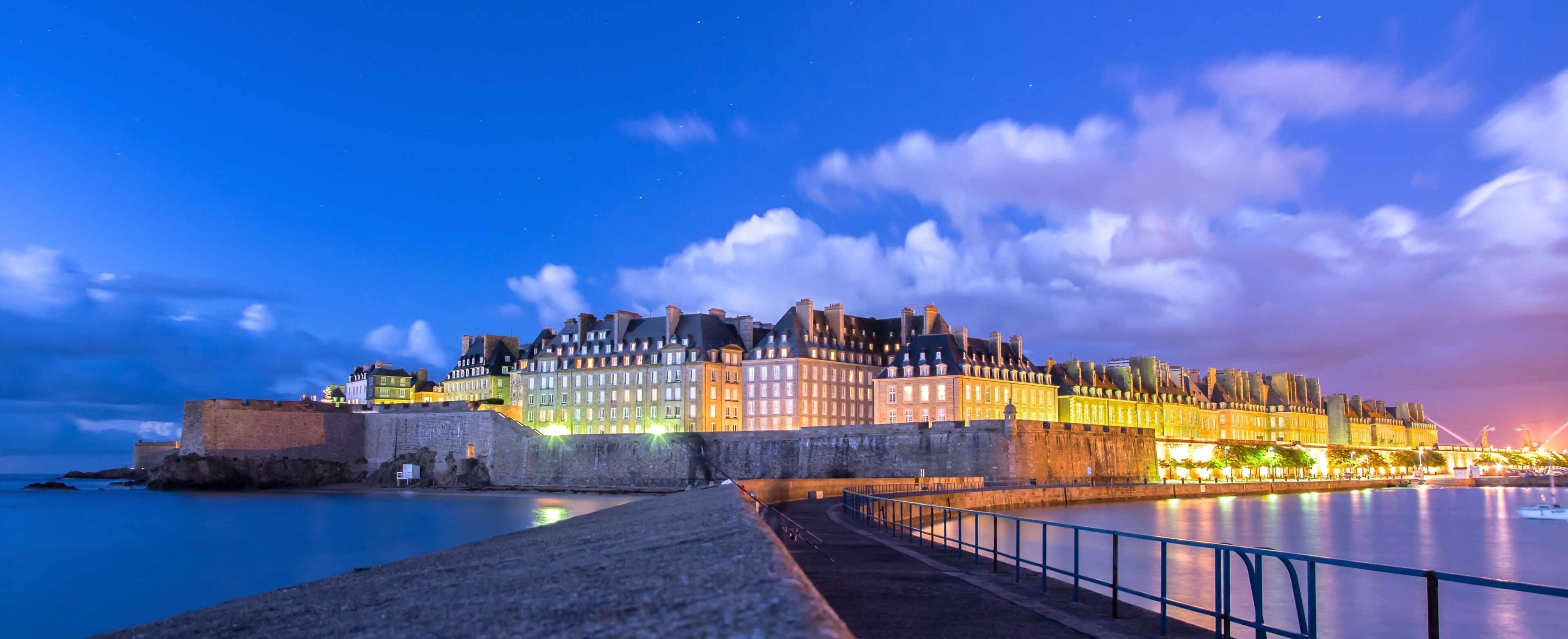 A historic walled city with illuminated buildings at dusk.