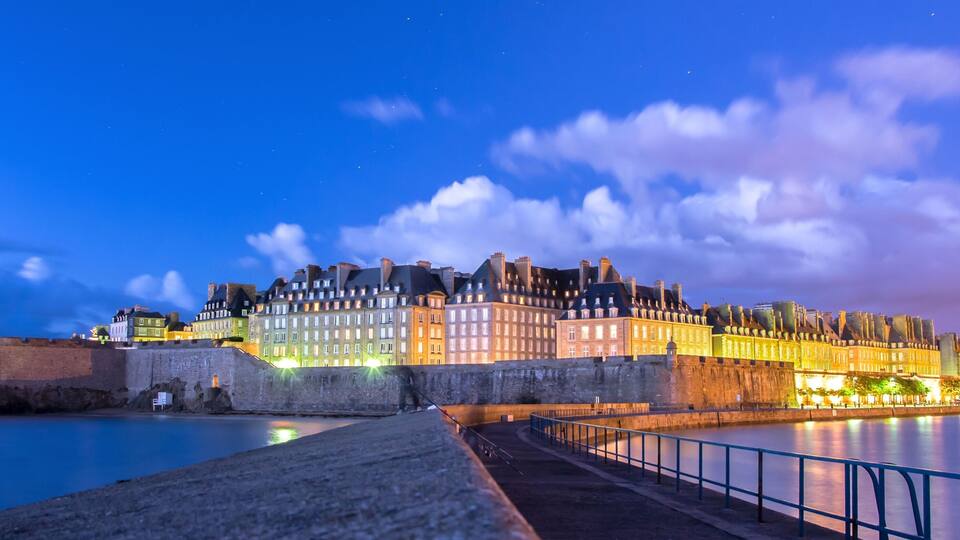 A historic walled city with illuminated buildings at dusk.