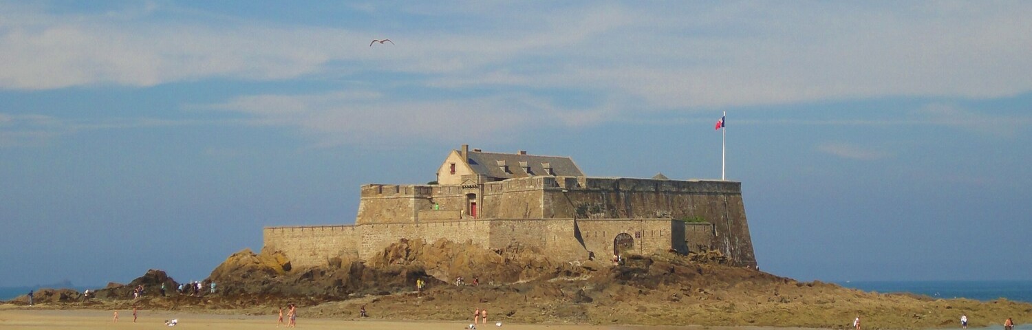Una fortificación costera con una playa arenosa al frente.