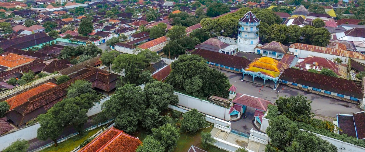An aerial view of a town with a prominent tower, surrounded by residential houses and greenery.