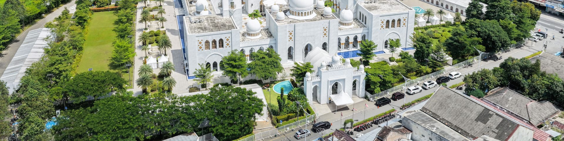 Aerial view of the Sheikh Zayed Grand Mosque Solo Surakarta with its white domes and minarets surrounded by the urban landscape of the city Kecamatan Banjarsari, Jawa Tengah, Indonesia.
