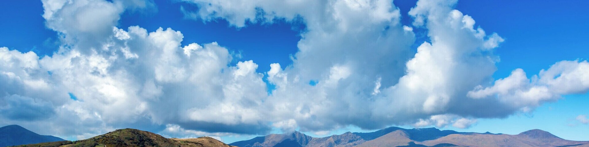 Un lago con montañas al fondo y un cielo azul despejado con nubes.