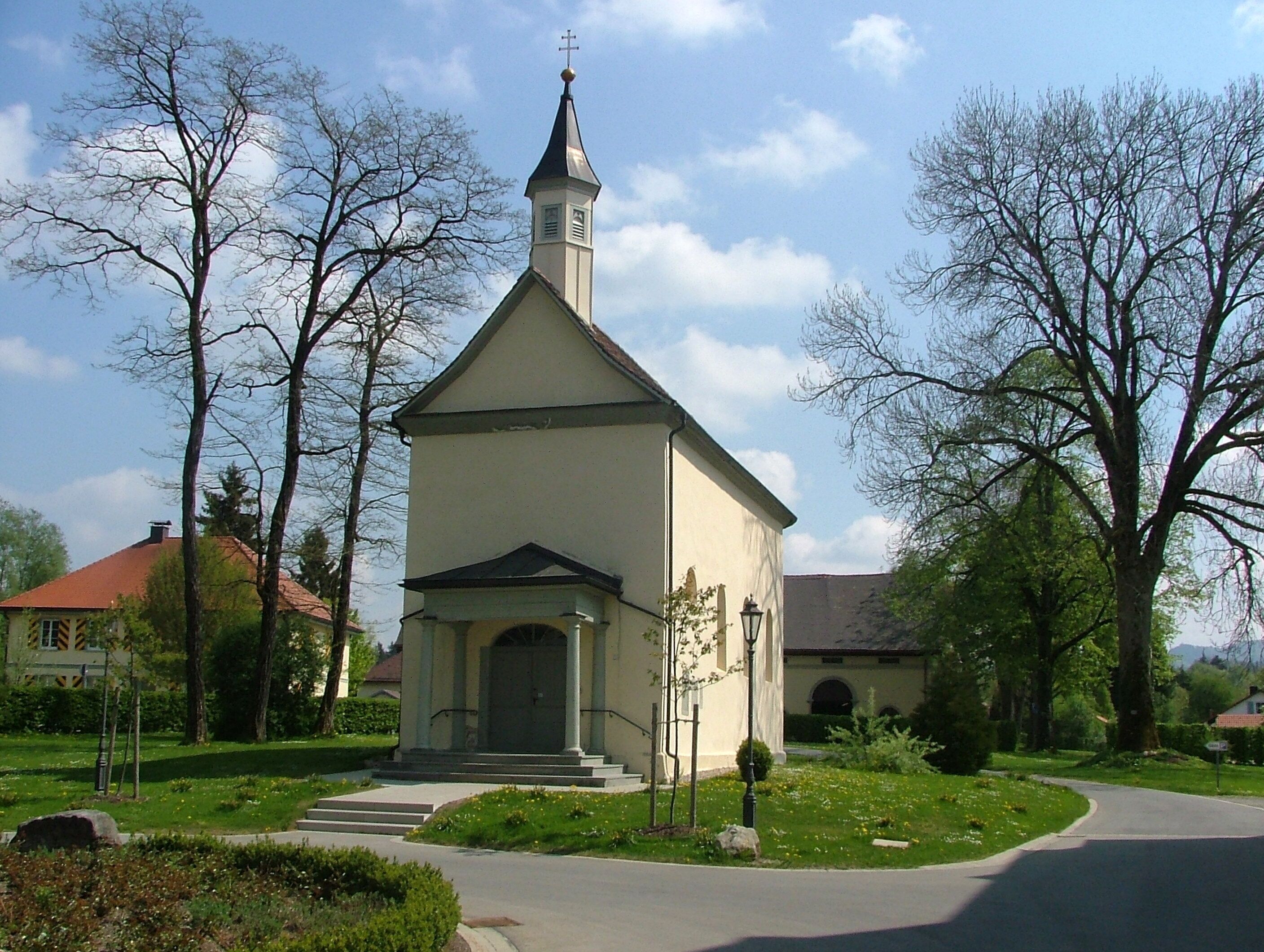 A small church with a steeple, surrounded by trees and a well-maintained lawn.