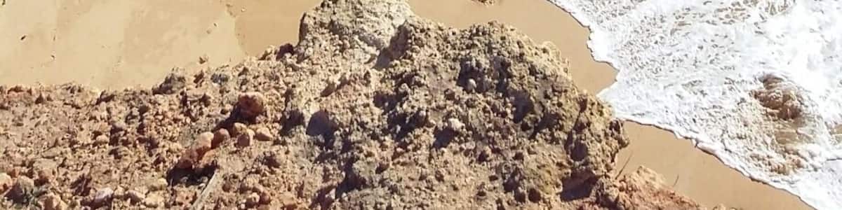 Un paysage côtier caractérisé par une arche rocheuse imposante et une plage de sable.