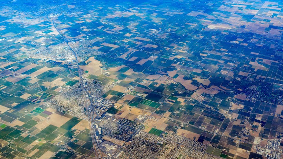 An aerial view of a patchwork of fields and a winding road.