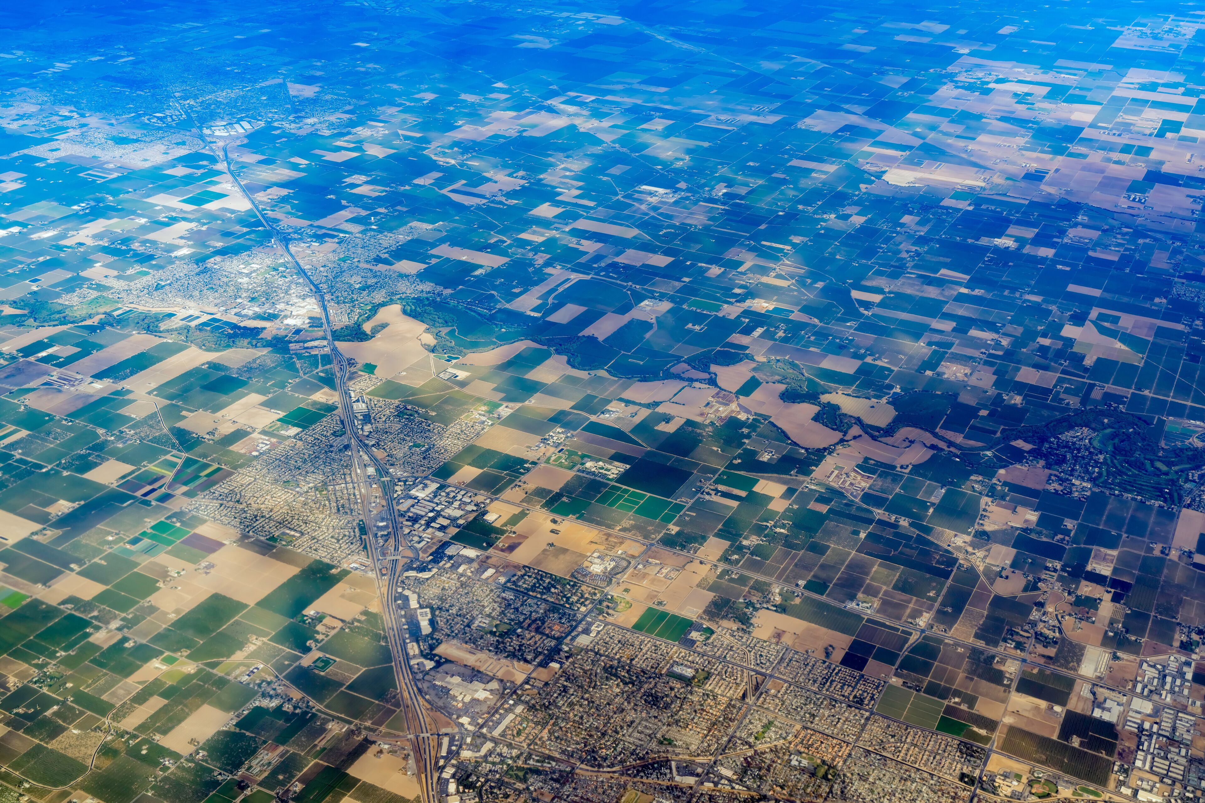 An aerial view of a patchwork of fields and a winding road.