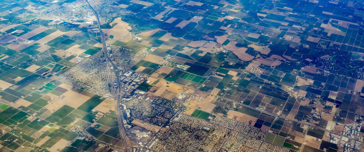 An aerial view of a patchwork of fields and a winding road.